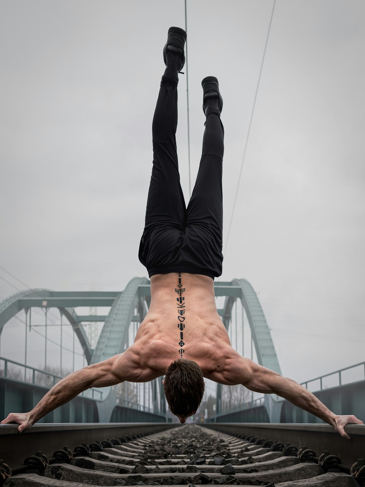 Athlete performing a handstand on a railway bridge